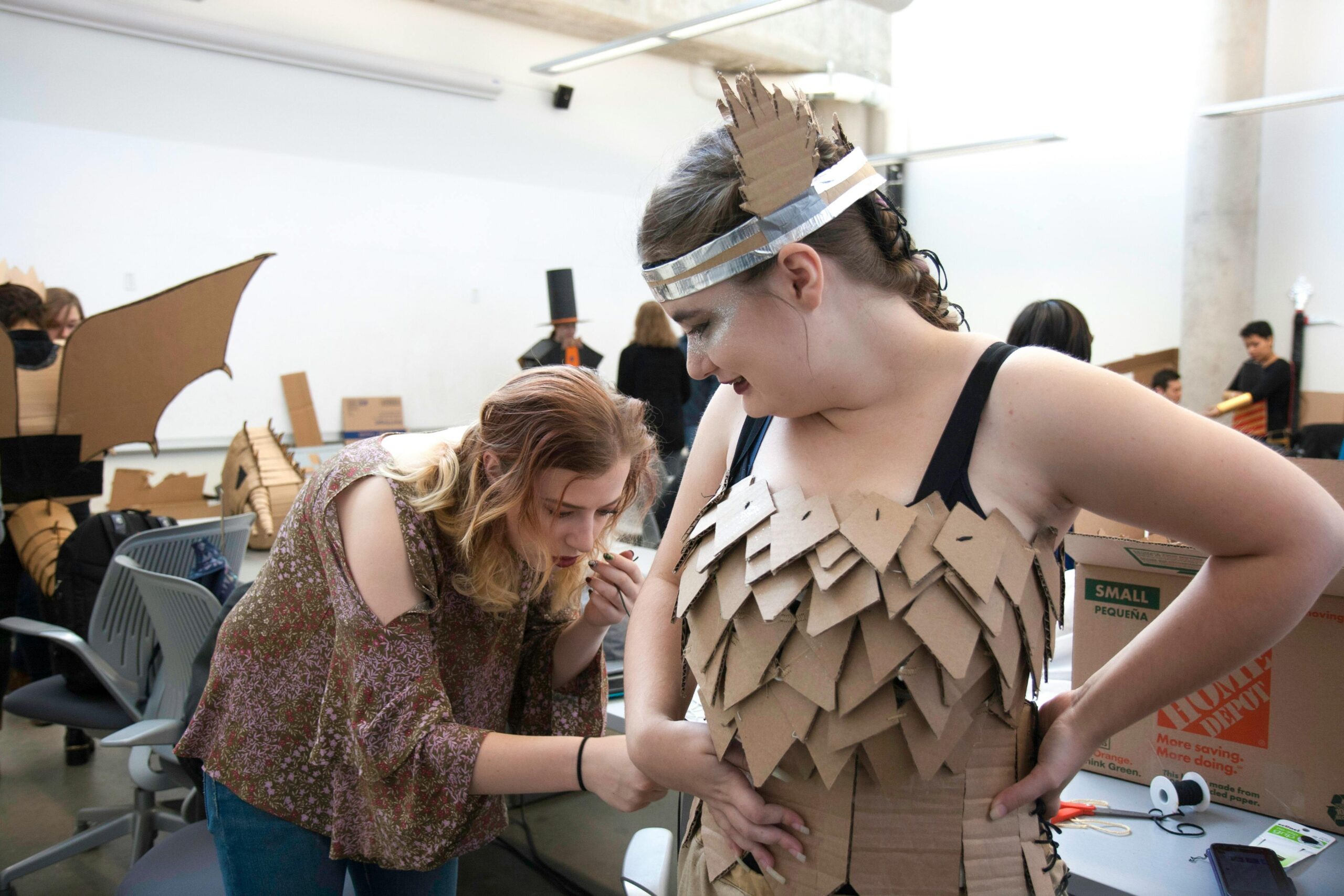 Woman checking her colleague s cut out carton box costume